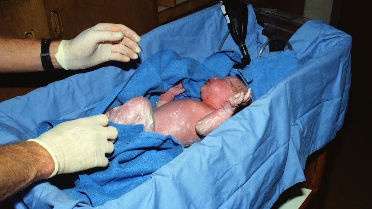 Newborn baby receiving medical care in a hospital cradle after birth.