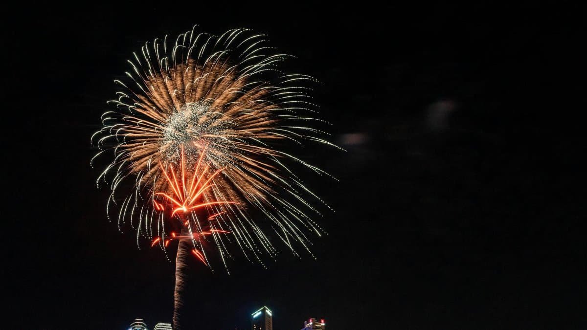 Vibrant fireworks light up the night sky over a modern city skyline, creating a festive atmosphere.