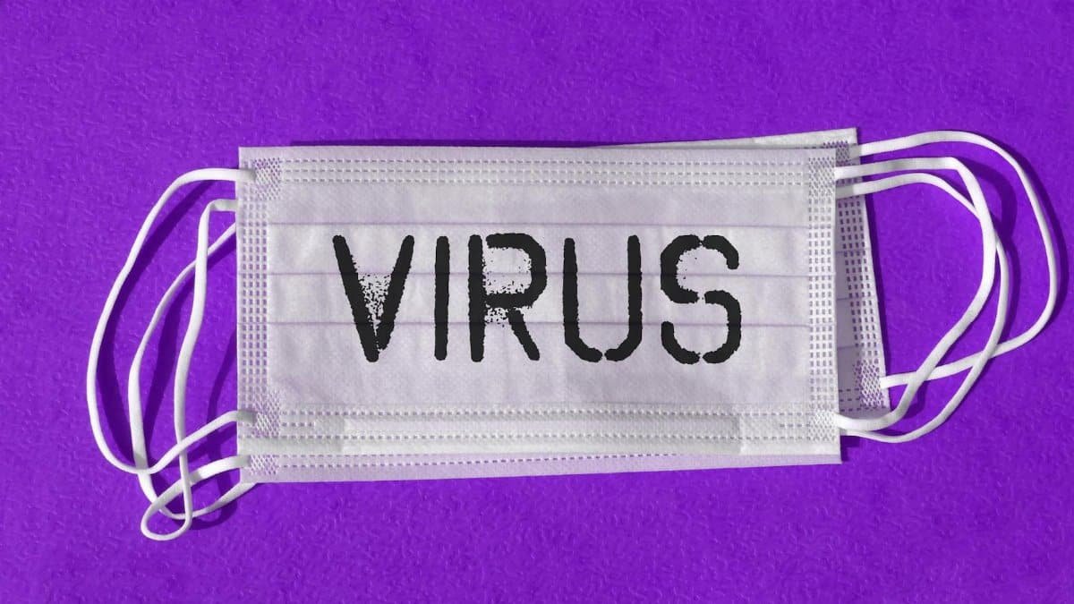 Close-up of a surgical mask with 'Virus' text against a purple backdrop symbolizing pandemic protection.