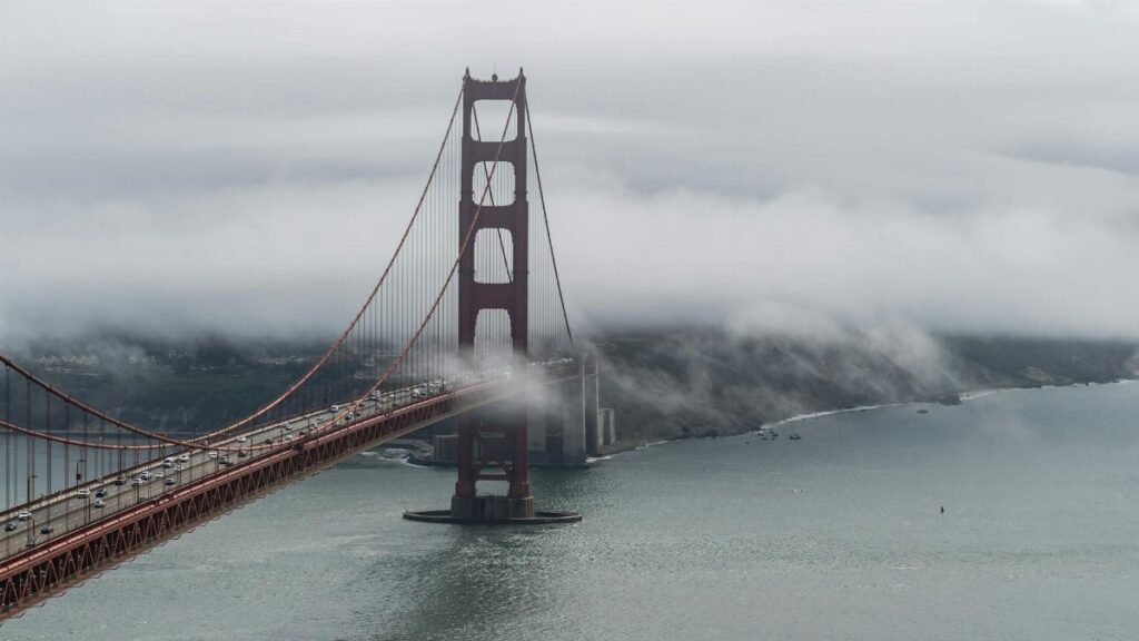 Aerial view of the Golden Gate Bridge enveloped in fog over San Francisco Bay.