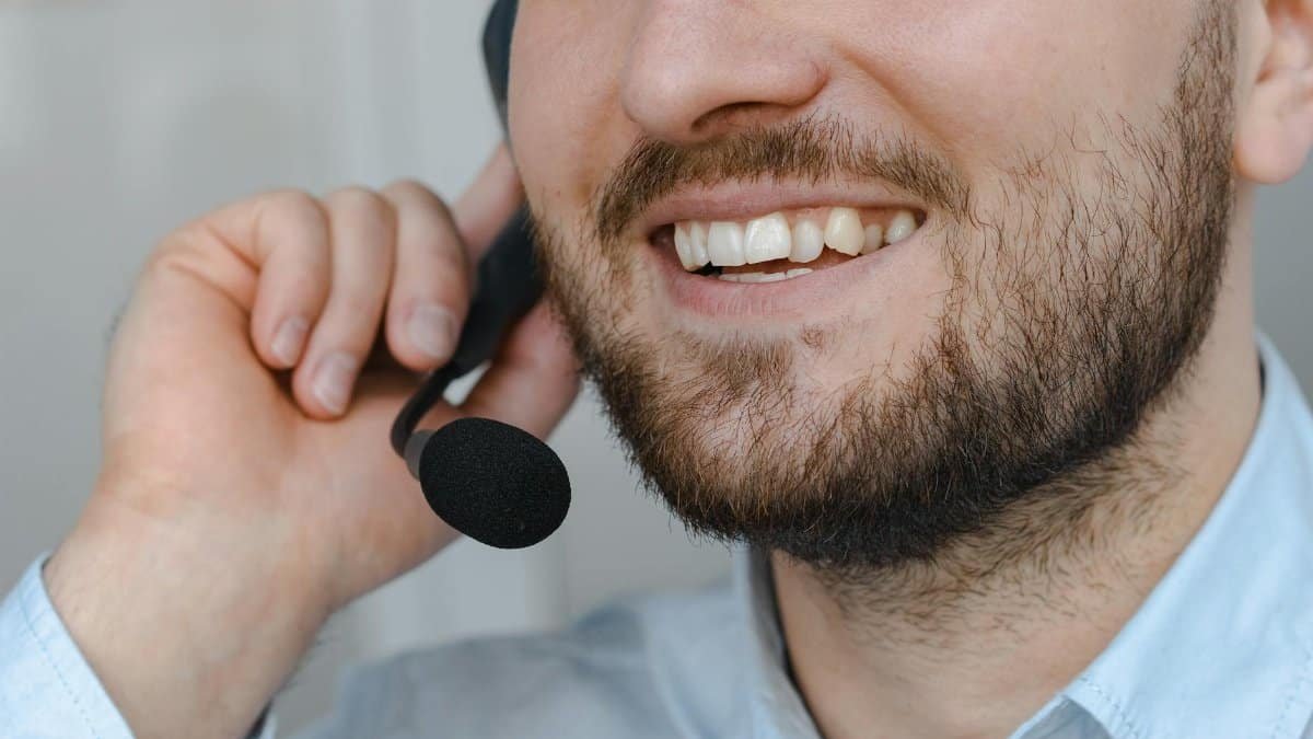 Close-up of a smiling customer support agent wearing a headset microphone.