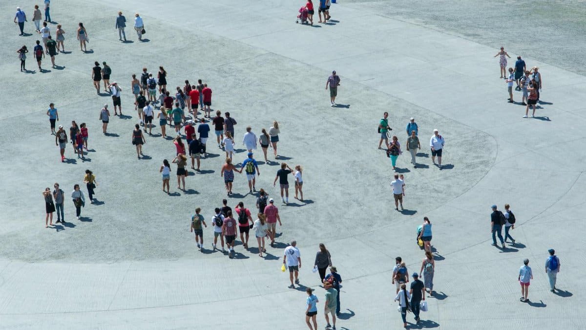 Aerial shot of diverse group of people walking in an open urban area on a sunny day.