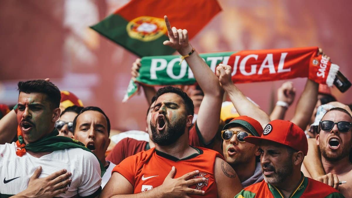 Passionate Portugal football supporters cheering with flags and scarves in vibrant celebration.