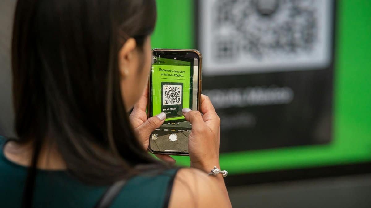 A woman uses her smartphone to scan a QR code in Mexico City, capturing modern technology in action.