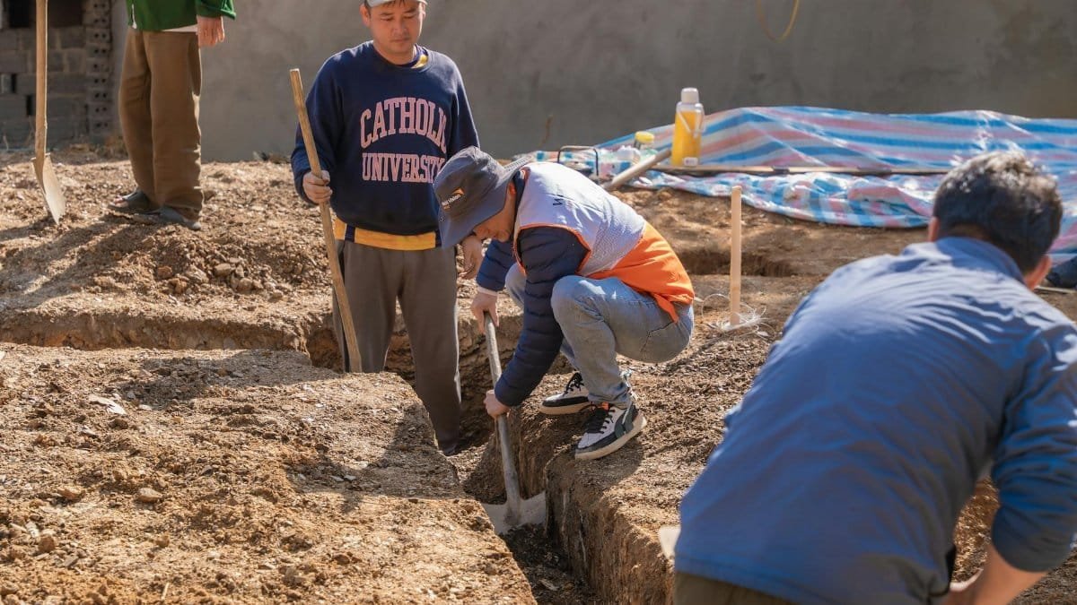 A group of four adult men working on a construction site digging a trench.