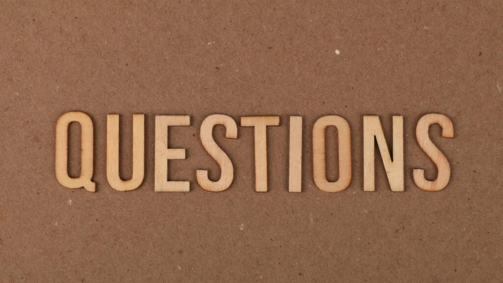Wooden letters spelling the word "QUESTIONS" on a cardboard background, providing a neutral copyspace.