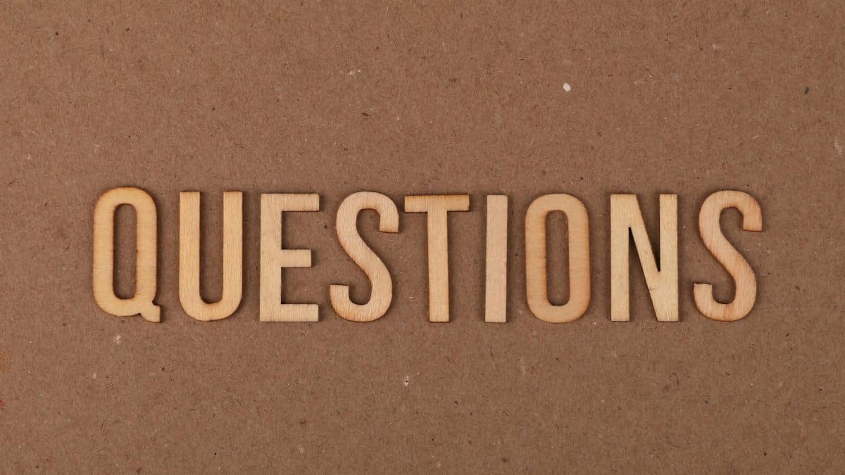 Wooden letters spelling the word "QUESTIONS" on a cardboard background, providing a neutral copyspace.