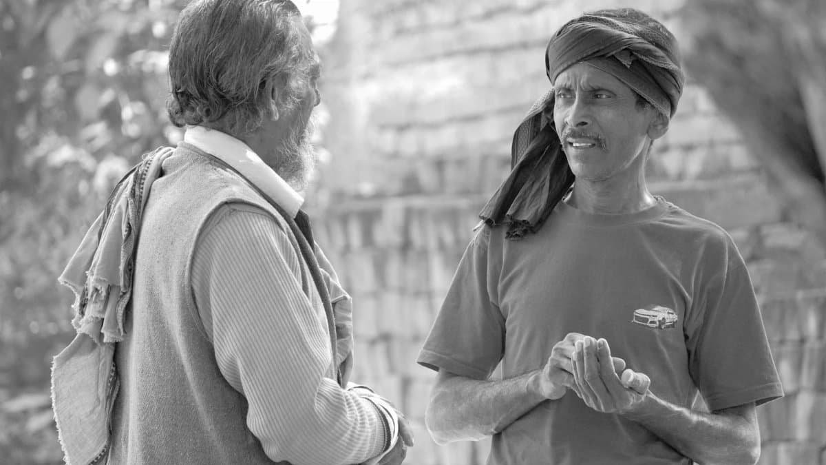 Two men engaging in a candid conversation on a rural street in Patna, India.