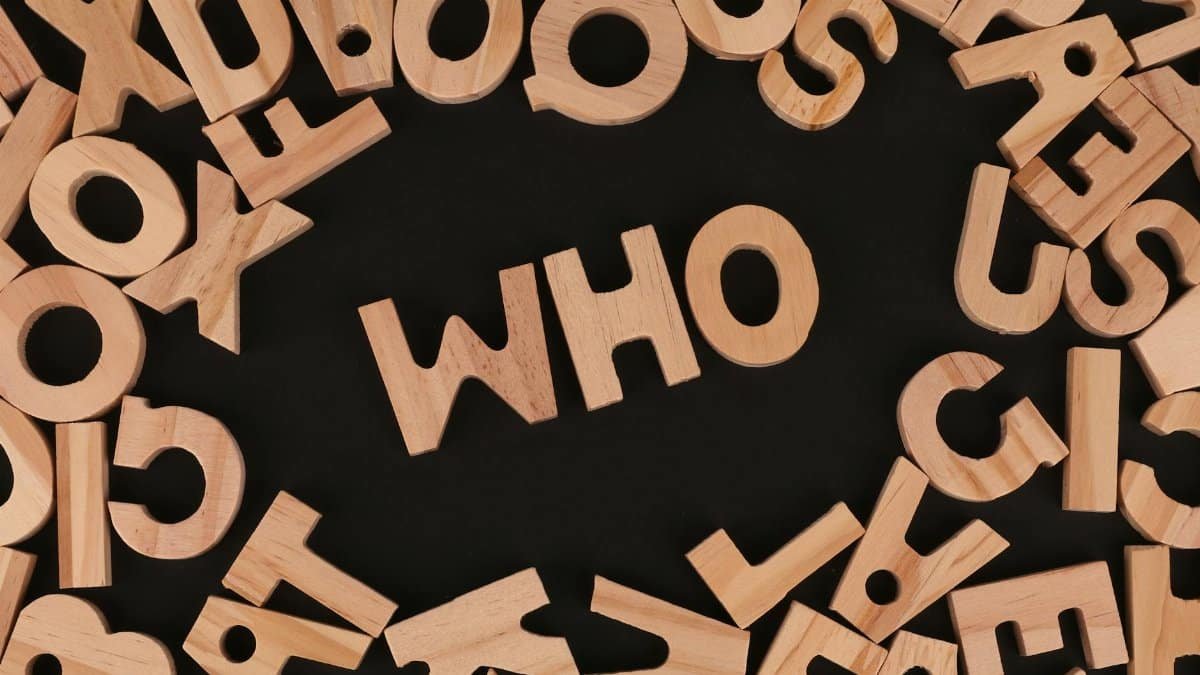 Wooden alphabet letters arranged to spell 'Who' on a black surface, creative message concept.