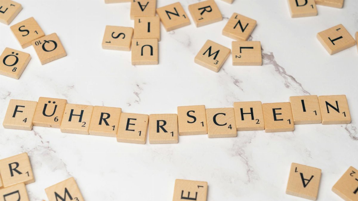 Scrabble tiles arranged to spell 'Führerschein' on a marble surface, representing language and word games.