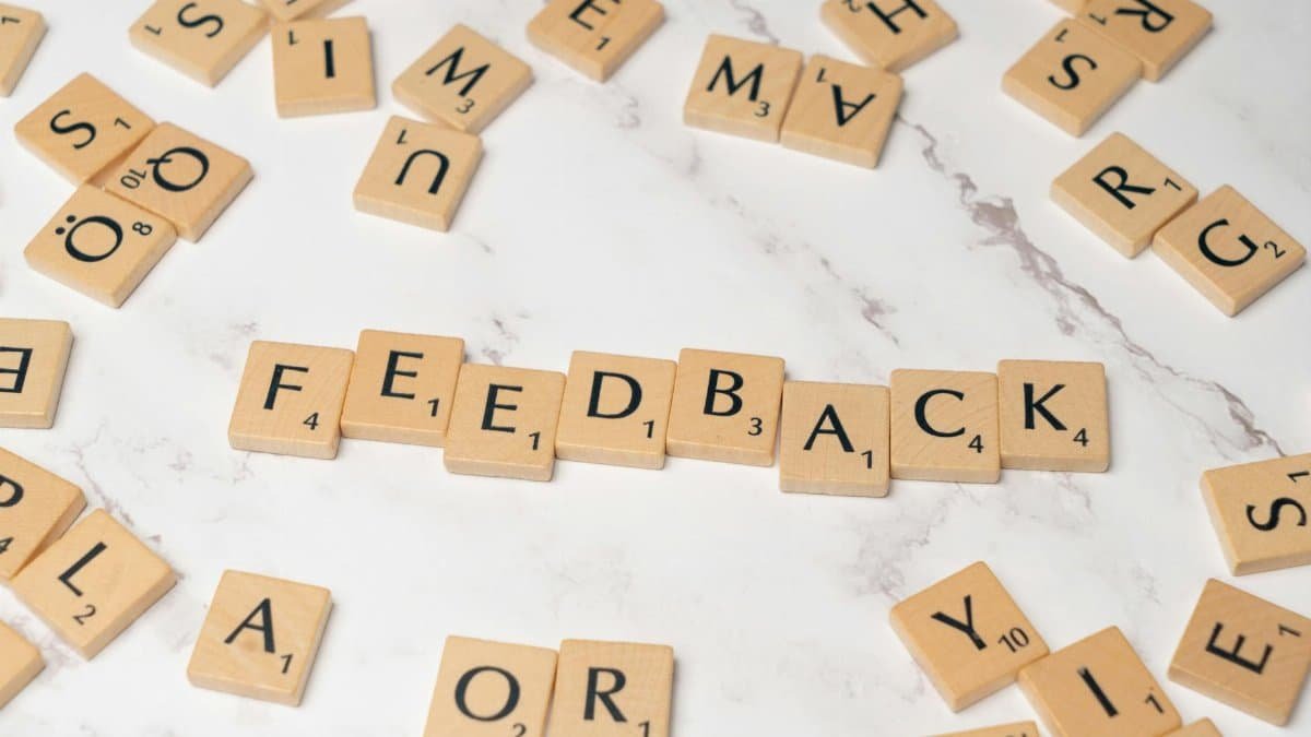 Wooden Scrabble tiles arranged to spell 'Feedback' on a marble background.