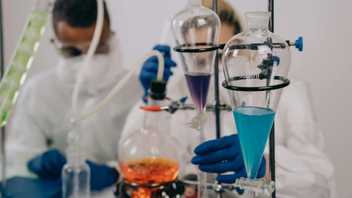 Scientists in protective gear conducting chemical experiments in a lab environment.