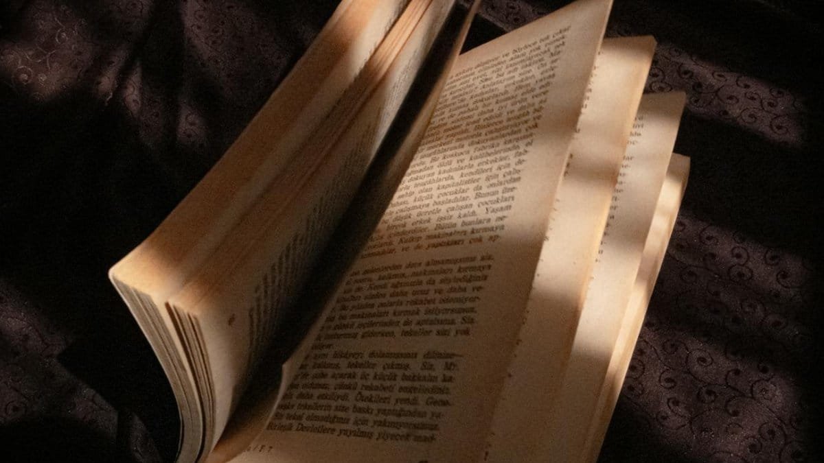 An open vintage book on a dark cloth, showcasing dramatic light and shadow play.