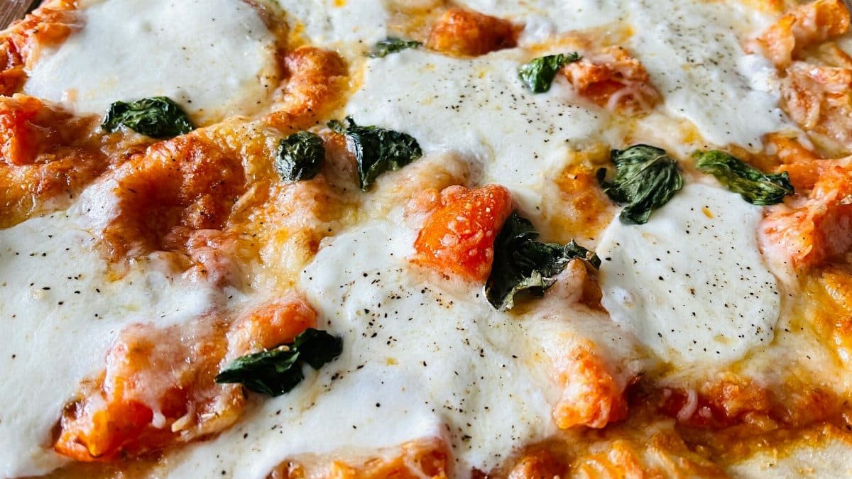Savory close-up of a hot, cheesy Margherita pizza topped with fresh basil and mozzarella.