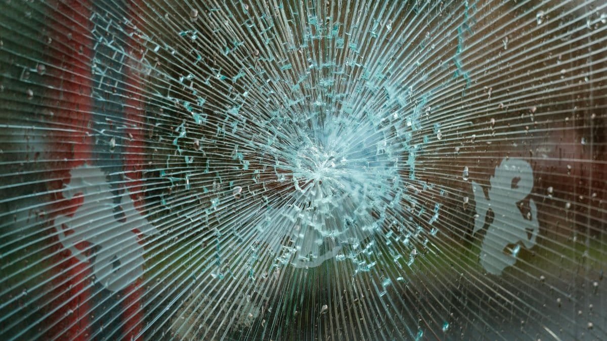 Close-up of a shattered glass panel displaying a radial crack pattern, perfect for abstract textures.