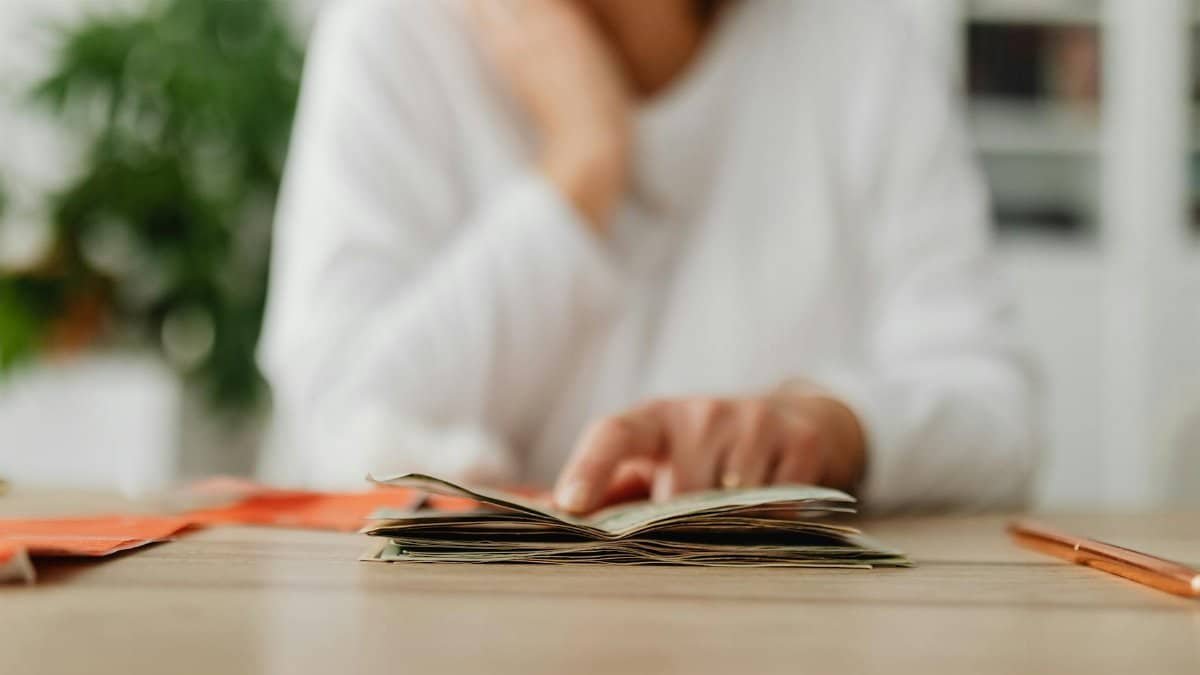 A woman sitting at a desk sorting through cash, focusing on household budgeting.