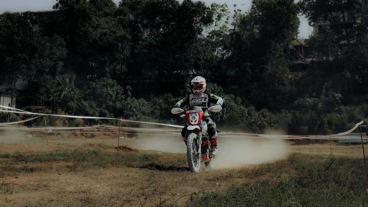 An adventurous motorcyclist races through a dusty outdoor dirt track.