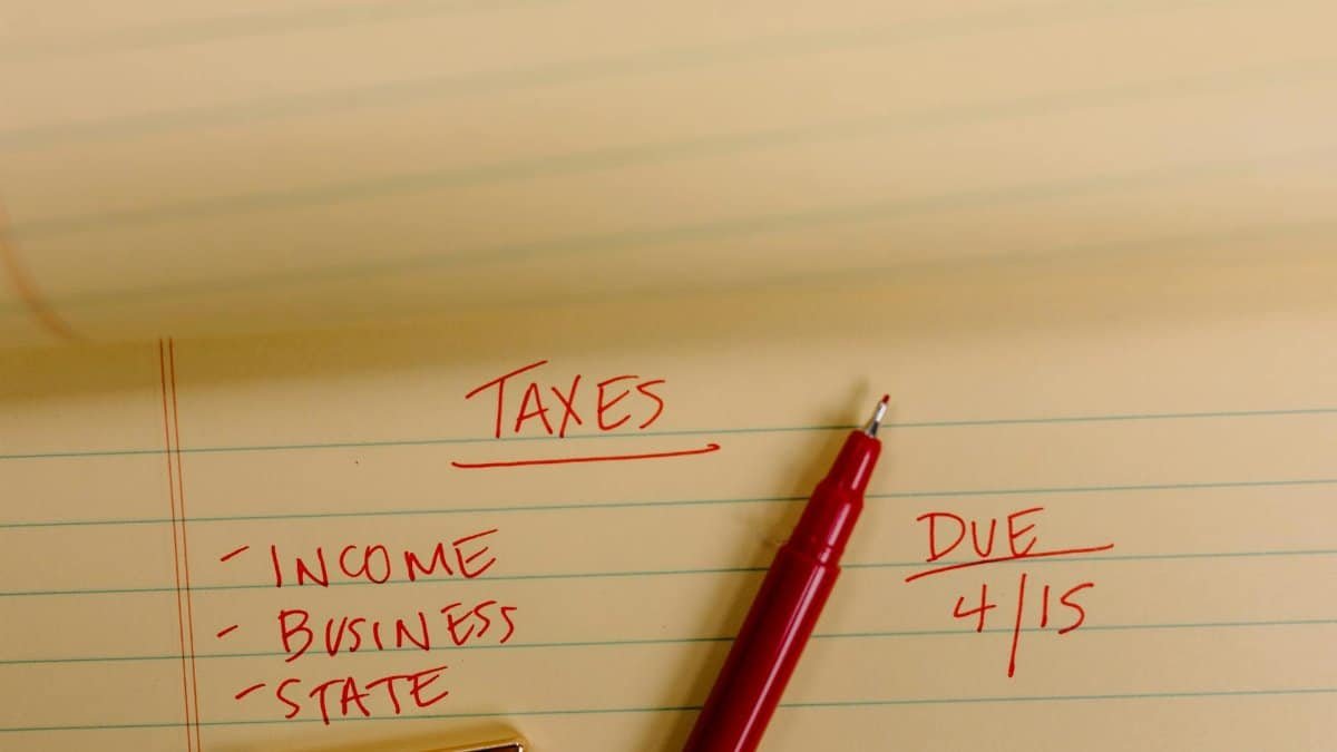 Close-up of tax-related notes on a yellow legal pad with red pen, highlighting important due dates.