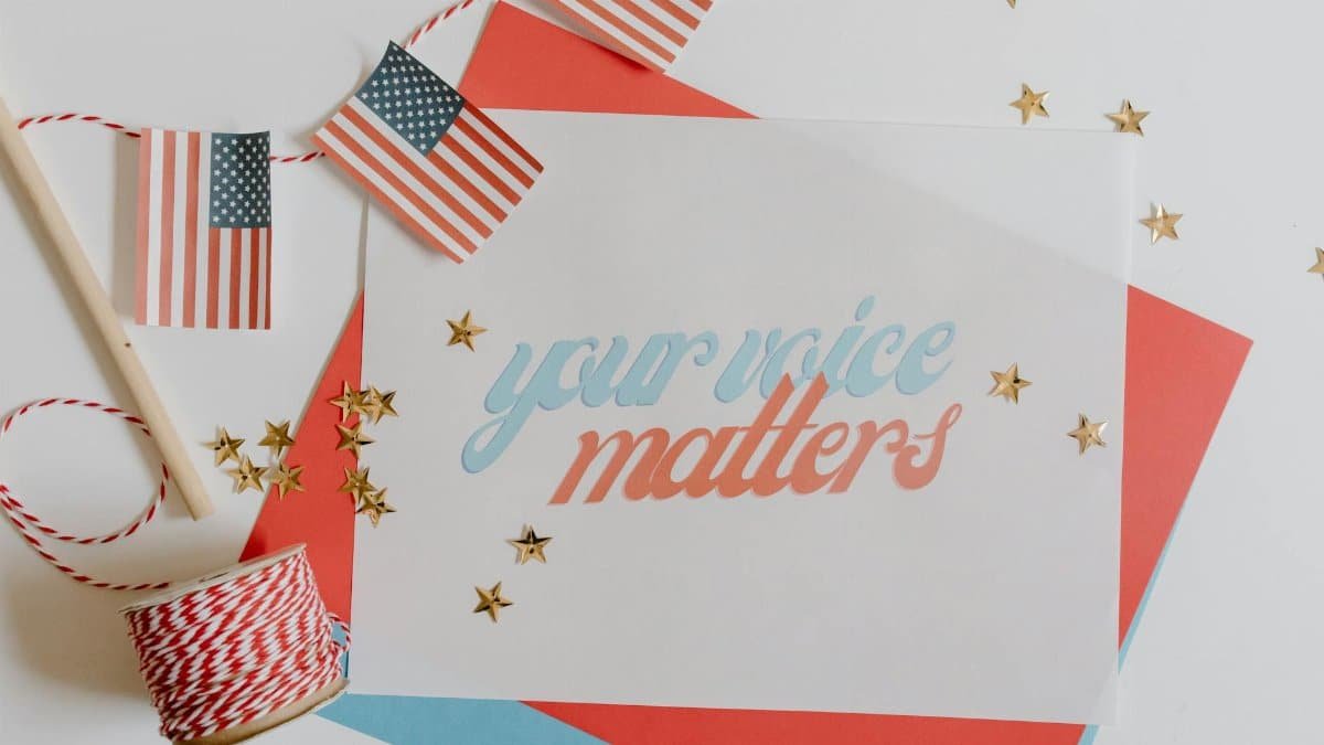 Flat lay of 'Your Voice Matters' with American flags and stars on a white background.