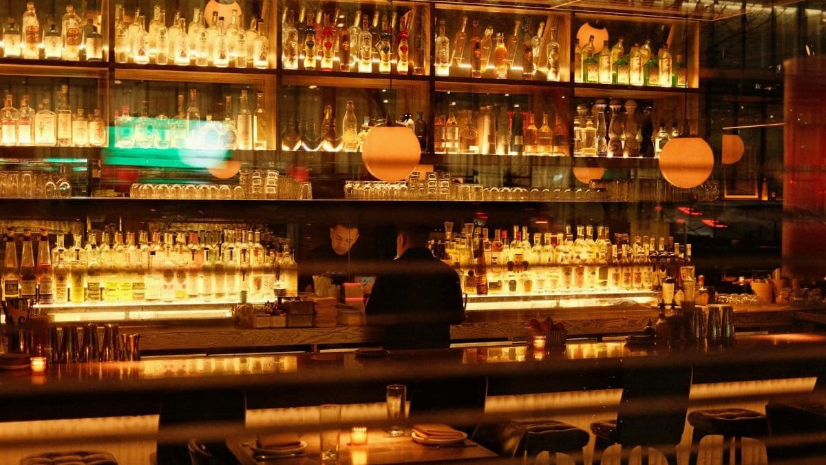 Warm and inviting bar interior in New York, featuring illuminated shelves of bottles and soft ambient lighting.