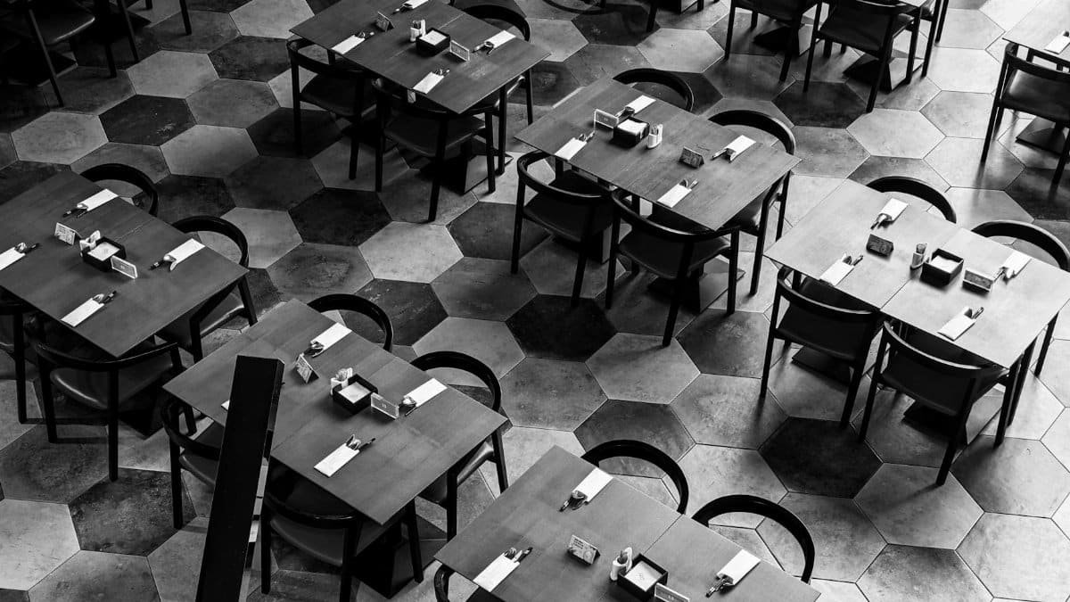 High angle view of empty tables and chairs in a modern restaurant with a hexagonal tile floor.