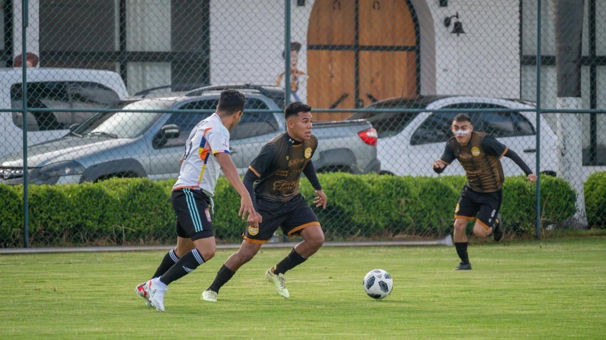 Action-packed scene of players competing in a football match on a sunny day in Texcoco, Mexico.