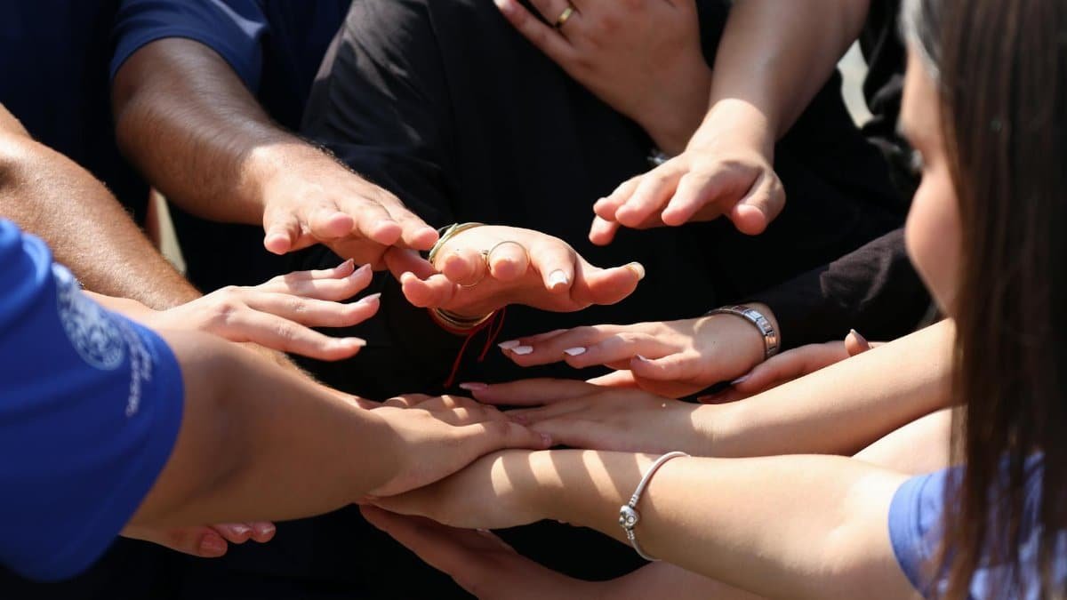 Hands coming together in a circle symbolizing unity, teamwork, and community spirit.