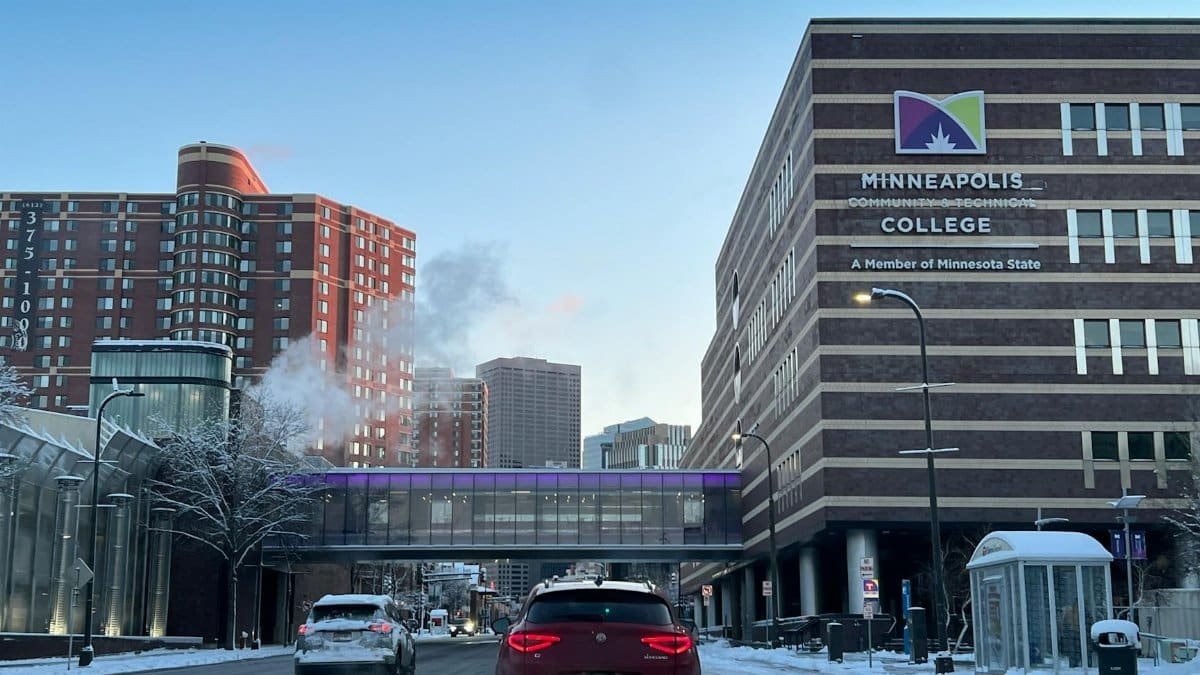 Snowy city street view featuring Minneapolis College and surrounding buildings in winter.
