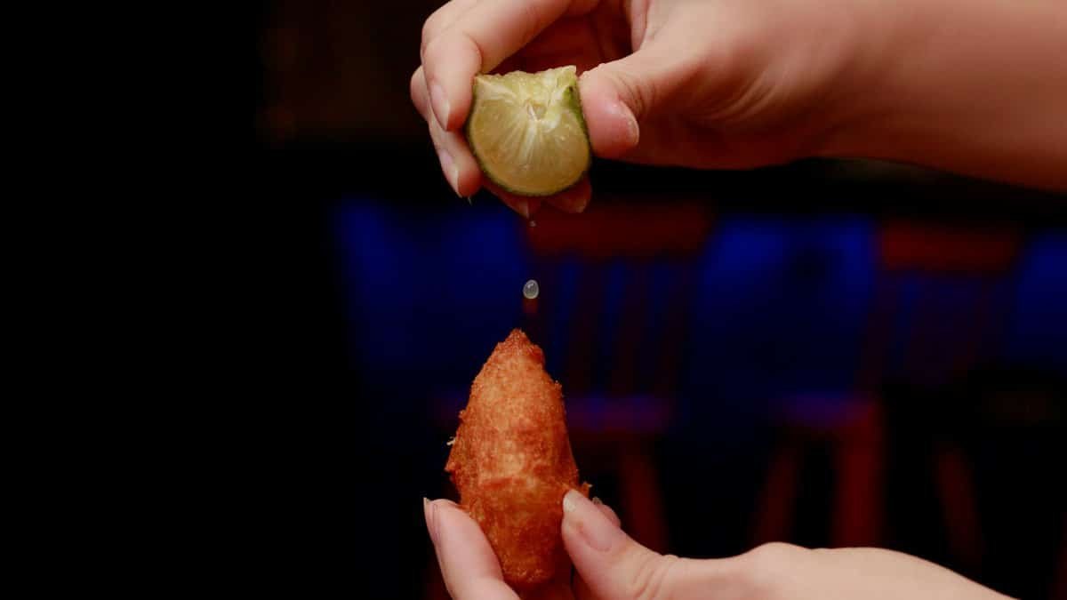 Close-up of lime being squeezed over a fried snack in Recife, Brazil.