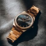 Close-up of a gold analog watch with a sleek design, artfully lit to highlight its elegance and style.