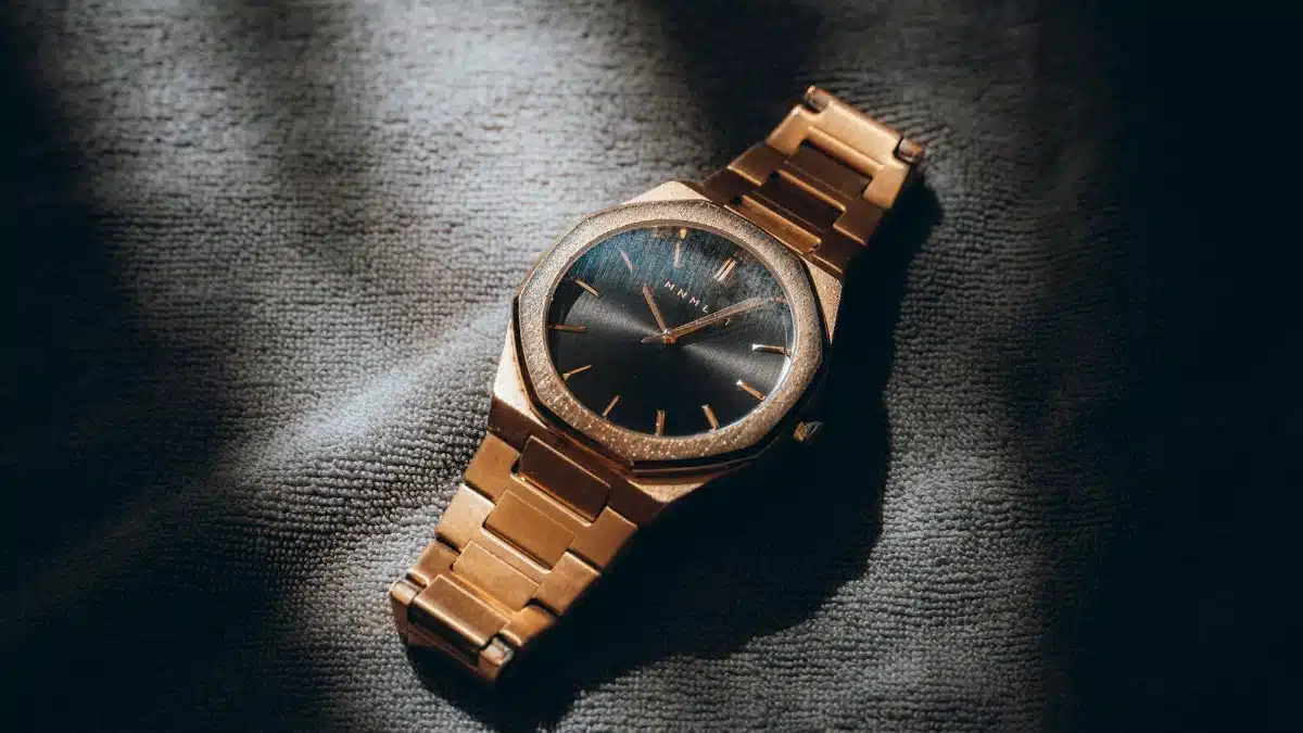 Close-up of a gold analog watch with a sleek design, artfully lit to highlight its elegance and style.
