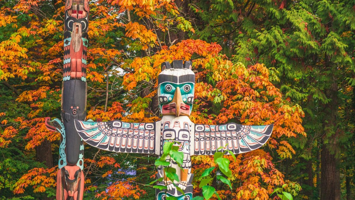 Vibrant totem pole amidst autumn foliage in Vancouver, Canada, showcasing indigenous art.