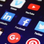 Close-up of a smartphone screen showing various social media app icons such as Facebook and Twitter.