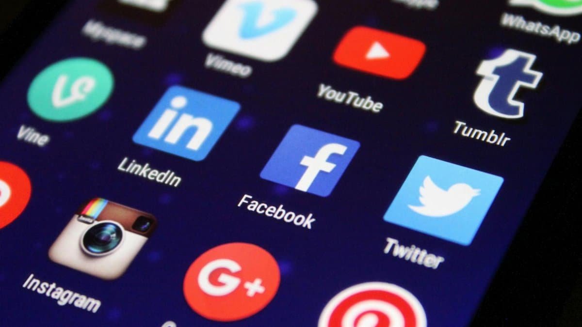 Close-up of a smartphone screen showing various social media app icons such as Facebook and Twitter.