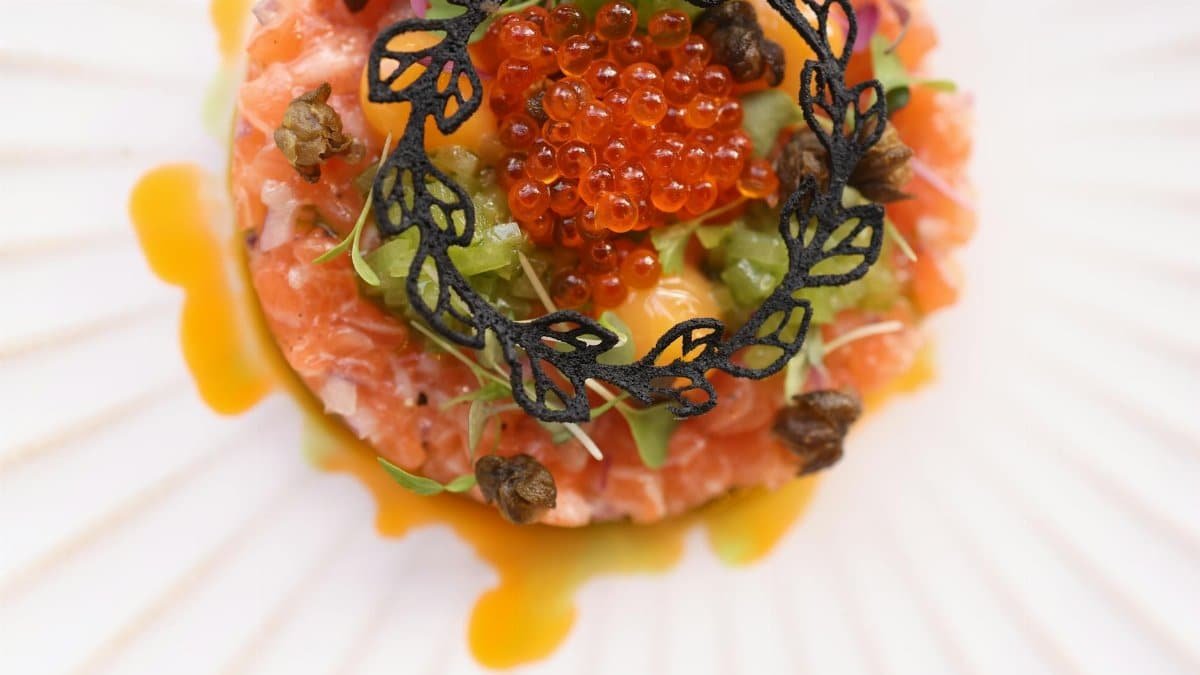 Top view of gourmet salmon tartare garnished with caviar on a decorative plate.