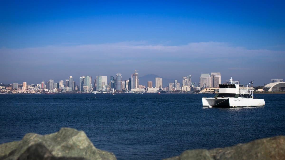 Bright view of San Diego's skyline with a boat on the bay, showcasing urban and maritime beauty.