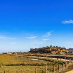 Peaceful rural landscape with dirt path and clear blue sky, perfect for relaxation.