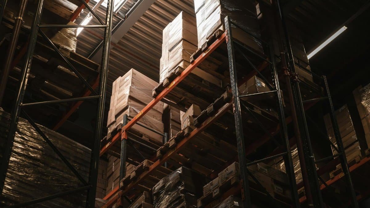 Interior view of a warehouse with stacked cardboard boxes on high shelves, showcasing storage and logistics.
