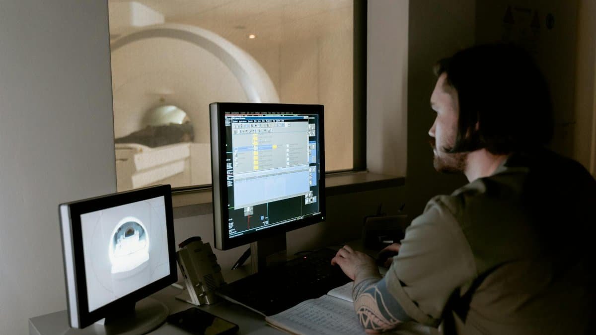 A radiologist examines MRI scan results on computer monitors in a medical facility.