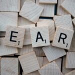 Wooden letter tiles arranged to spell 'learn' on a background of scattered tiles.