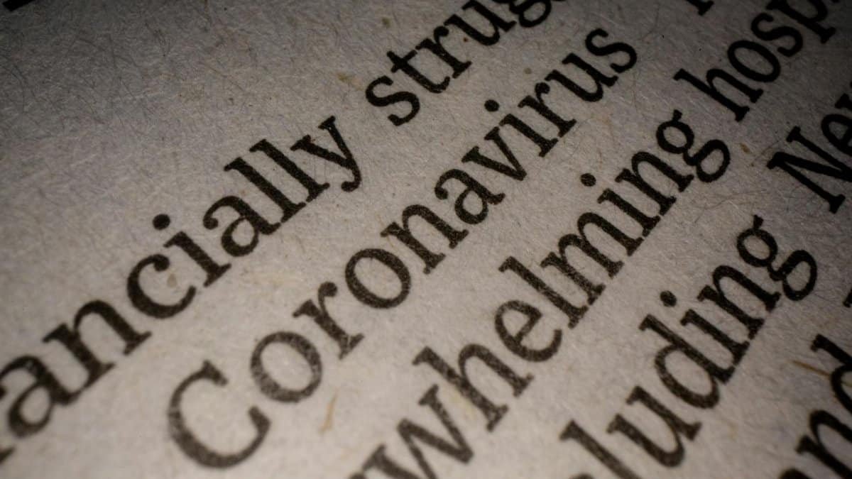 Closeup white page of article with black font about coronavirus pandemic research and economy impact