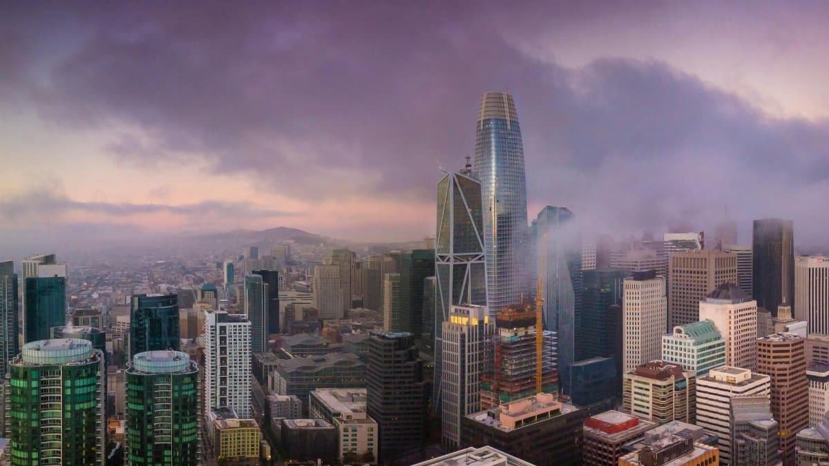 Aerial view of San Francisco's skyline at sunset with iconic skyscrapers and dramatic clouds.