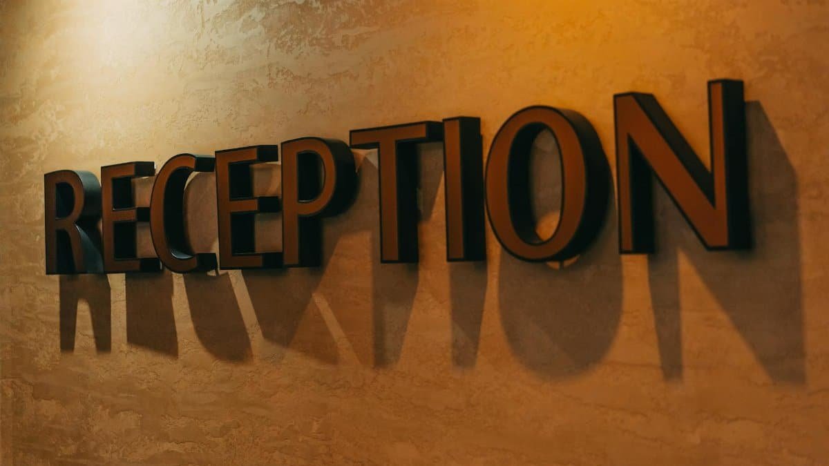 Elegant hotel reception sign casting dramatic shadows on textured wall.