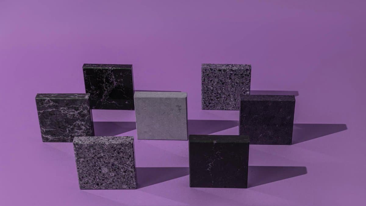 Minimalist arrangement of stone tiles on a purple background with strong shadows.