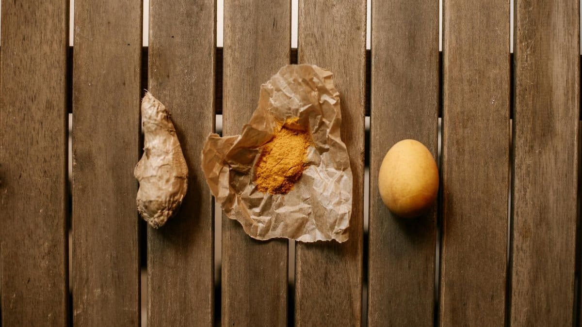 Top view of ginger, turmeric, and egg arranged on a wooden table.