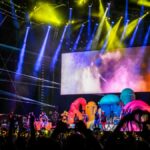 Energetic concert scene with colorful lights and performers on stage