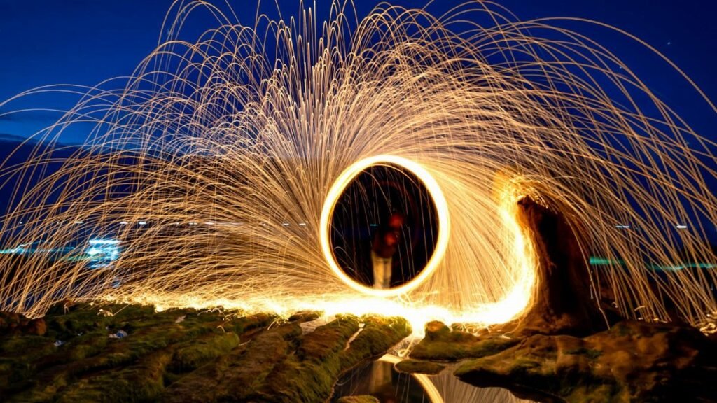 Captivating long exposure light painting with steel wool at night, creating mesmerizing sparks.