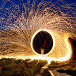Captivating long exposure light painting with steel wool at night, creating mesmerizing sparks.