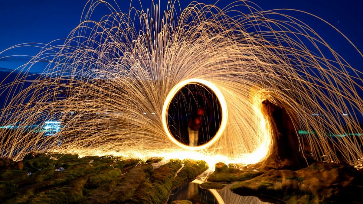 Captivating long exposure light painting with steel wool at night, creating mesmerizing sparks.