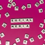 Alphabet tiles forming 'Social Media' on a vibrant pink background, perfect for digital marketing themes.